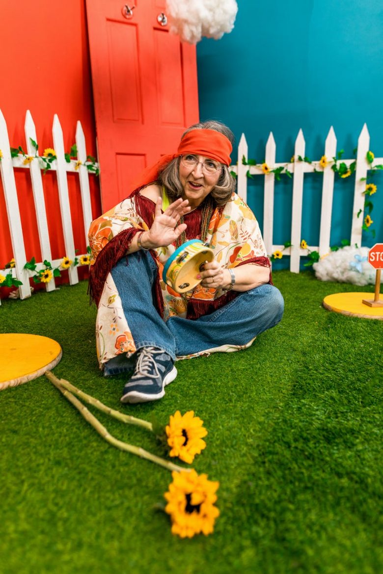 Woman In Blue Denim Jeans Sitting On Green Grass With A Tambourine